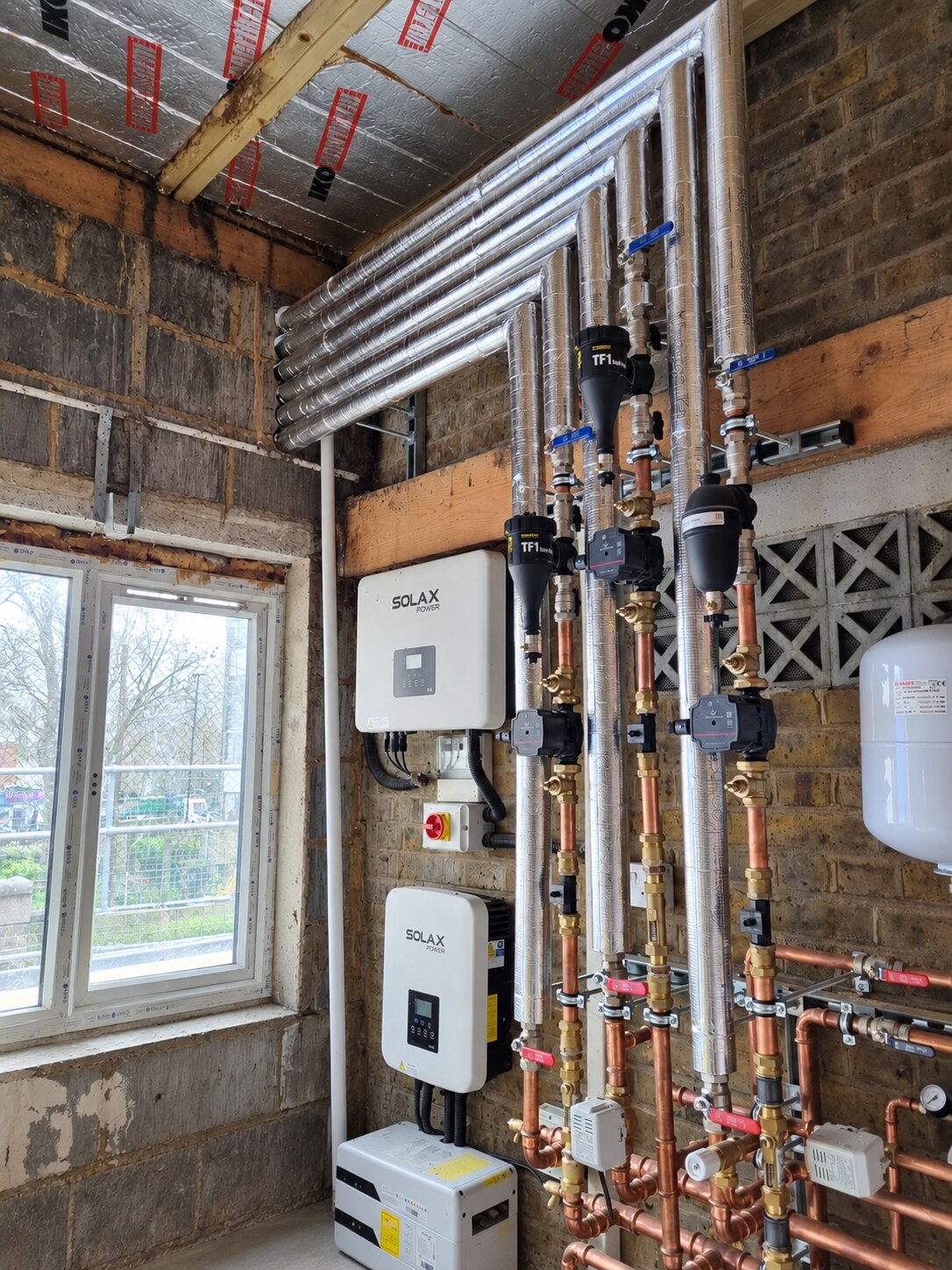 Coordinated insulated hydronic pipework and equipment for a multi-stage cascade air-source heat-pump installation