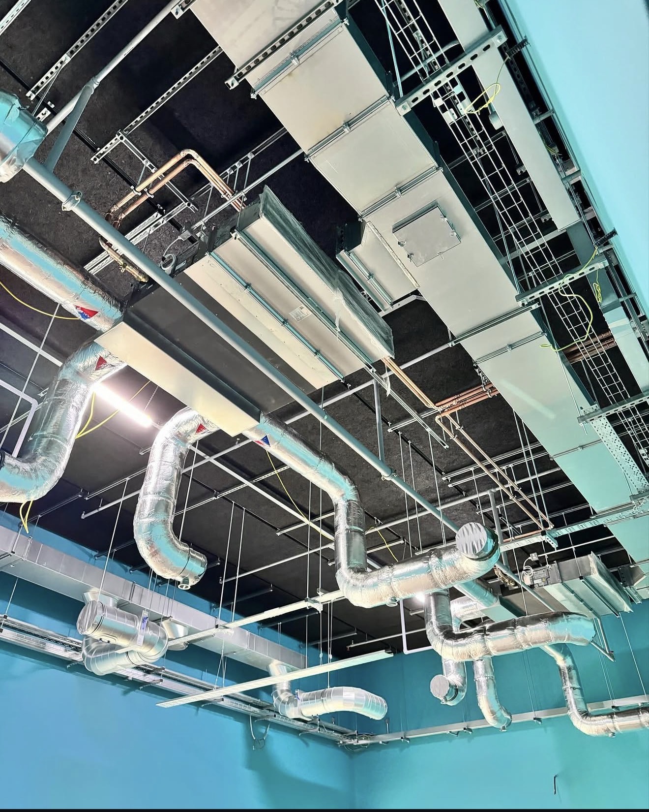High-level ducted air-conditioning units coordinated with exposed ventilation and building services
