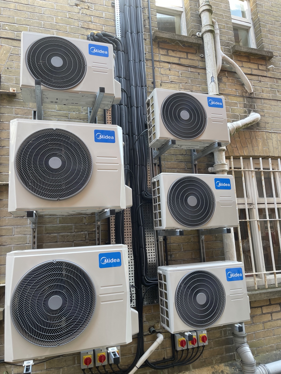 Six commercial outdoor air-conditioning units installed on wall brackets