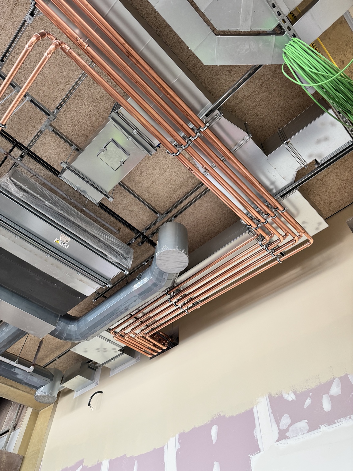 Multiple copper Hybrid VRF water lines routed neatly at high level around building services