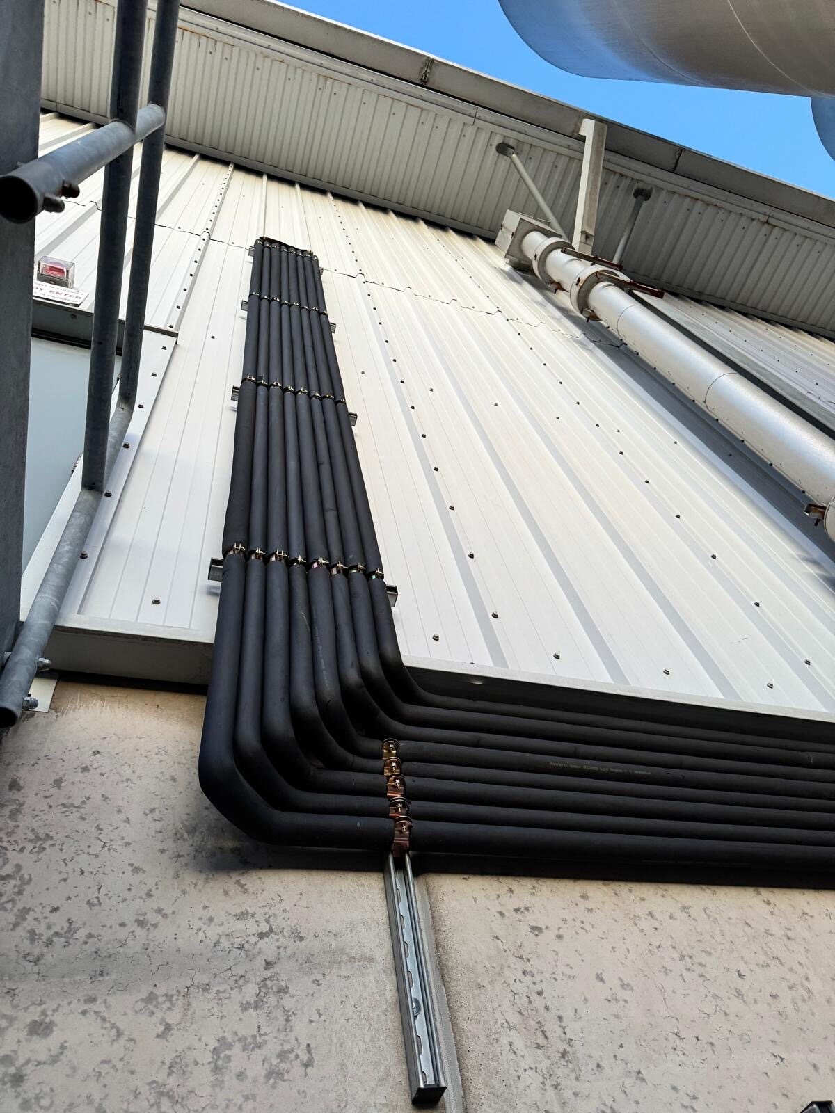 Multiple insulated refrigeration lines turning neatly up an external wall